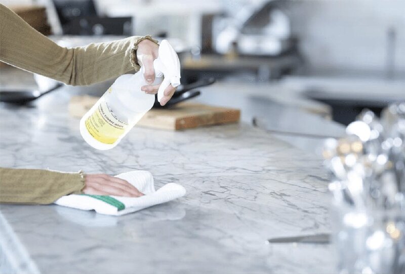 Person cleaning a stone countertop